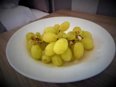 a bunch of grapes on a white plate on a table at Baron View Apartment in Paisley