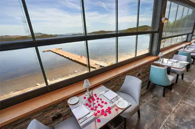 a restaurant with a view of the ocean and a pier at The Lodge On Loch Lomond Hotel in Luss