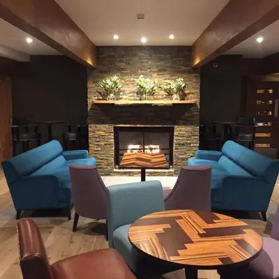 a living room with blue chairs and a fireplace at The Lodge On Loch Lomond Hotel in Luss