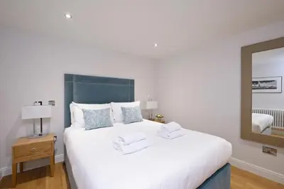 a bedroom with a large white bed with a mirror at Destiny Scotland New Town Apartments in Edinburgh