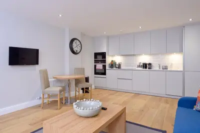 a living room with a table and a kitchen at Destiny Scotland New Town Apartments in Edinburgh