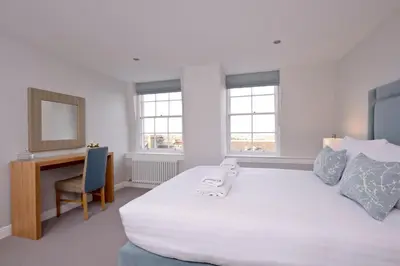 a bedroom with a large white bed and a desk at Destiny Scotland New Town Apartments in Edinburgh