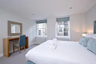 a bedroom with a large white bed and a desk at Destiny Scotland New Town Apartments in Edinburgh