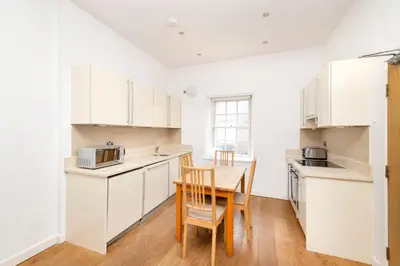 a kitchen with white cabinets and a table and chairs at JOIVY Superb Flats in the Heart of Edinburgh in Edinburgh