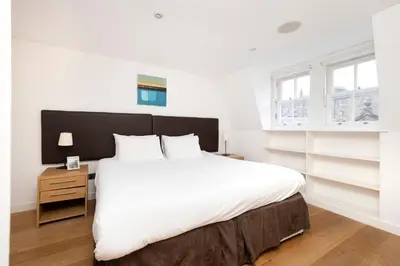 a bedroom with a large white bed and a night stand at JOIVY Superb Flats in the Heart of Edinburgh in Edinburgh