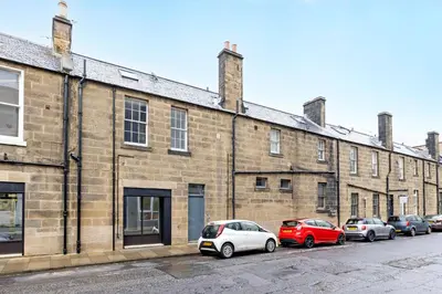 a row of cars parked in front of a brick building at JOIVY Superb Flats in the Heart of Edinburgh in Edinburgh