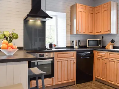 a kitchen with wooden cabinets and black appliances at Ardchoille Cottage in Fortingall
