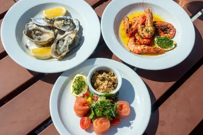 four plates of food on a table with seafood at Beach Houses with Hot Tubs in Glencoe