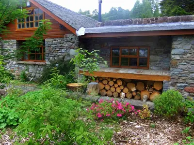 a house with a pile of logs in front of it at Loch Lomond shore Boat House in Balmaha