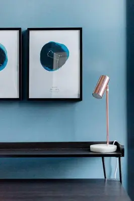 a blue wall with two pictures and a lamp on a table at Incredible contemporary flat in heart of west end in Glasgow