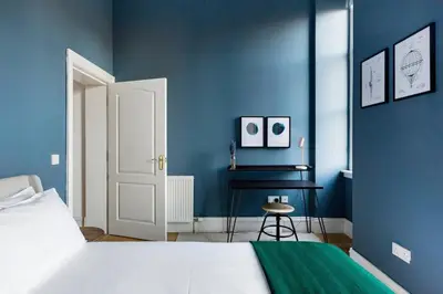 a blue bedroom with a bed and a table at Incredible contemporary flat in heart of west end in Glasgow