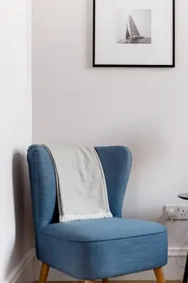 a blue chair sitting in a room with a picture at Incredible contemporary flat in heart of west end in Glasgow