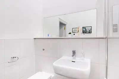 a white bathroom with a sink and a mirror at Incredible contemporary flat in heart of west end in Glasgow