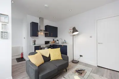 a living room with a couch and a kitchen at Dollar Apartments-39 Bridge Street in Dollar