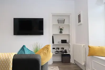 a living room with a couch and a tv on a wall at Dollar Apartments-39 Bridge Street in Dollar