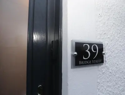 a sign on the side of a door with the number at Dollar Apartments-39 Bridge Street in Dollar