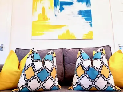 a couch with pillows and paintings on the wall at South Calder House in Wishaw