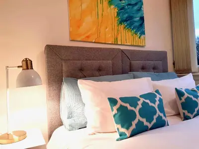 a bed with blue and white pillows and a lamp at South Calder House in Wishaw