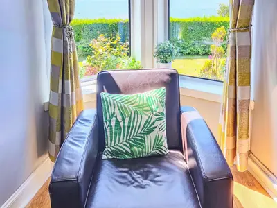 a leather chair with a pillow in front of a window at Firwood Apartment in Kilmun