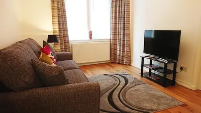 a living room with a couch and a flat screen tv at Violet Bank Apartment West End. in Edinburgh