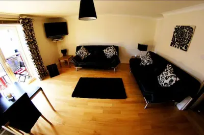 a living room with two black couches and a television at Ayr Holiday Apartment Donnini Court in Ayr