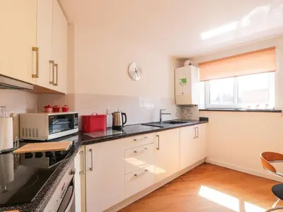 a kitchen with white cabinets and black counter tops at Ayr Holiday Apartment Donnini Court in Ayr