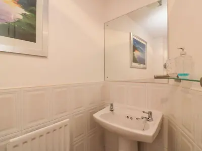 a white bathroom with a sink and a mirror at Ayr Holiday Apartment Donnini Court in Ayr