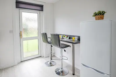 a kitchen with a table and two chairs and a refrigerator at Stirling Mercury Apartment - Scotland Holiday Let in Stirling