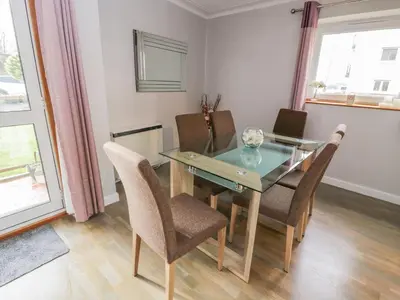 a dining room with a glass table and chairs at Cumbrae View in Largs