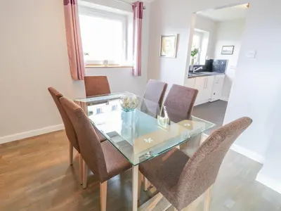 a dining room with a glass table and chairs at Cumbrae View in Largs