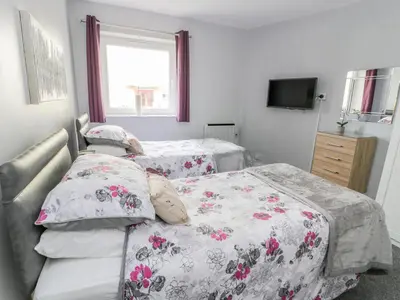a bedroom with two beds and a window at Cumbrae View in Largs