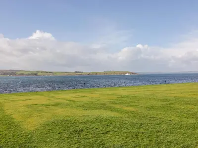 a grassy field next to a body of water at Cumbrae View in Largs
