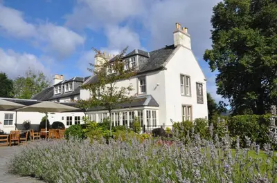 a large white house with a garden in front of it at The Loch Lomond Arms Hotel in Luss
