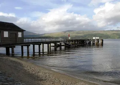 a pier on the water with a house on it at The Loch Lomond Arms Hotel in Luss