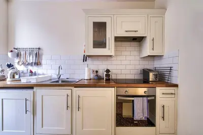 a kitchen with white cabinets and a sink at JOIVY Stylish Home in New Town in Edinburgh