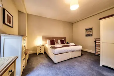 a bedroom with a large bed and a dresser and a bed sidx sidx sidx at JOIVY Stylish Home in New Town in Edinburgh