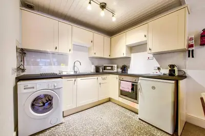 a kitchen with white cabinets and a washer and dryer at JOIVY Charming Apt close to City Centre in Edinburgh