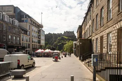 a city street with buildings and a castle in the background at JOIVY Charming Apt close to City Centre in Edinburgh