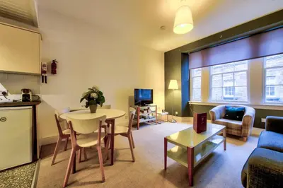 a living room with a table and a couch and a kitchen at JOIVY Charming Apt close to City Centre in Edinburgh