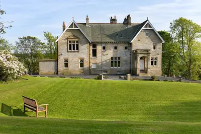 a large stone house with a bench in the grass at Balmule House in Dunfermline