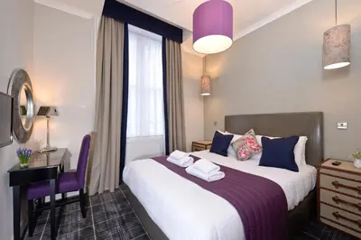 a hotel room with a bed and a desk and a window at Destiny Scotland Charlotte Square Apartments in Edinburgh