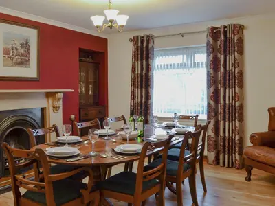 a dining room with a table and chairs and a fireplace at Hawthorn Cottage in Stranraer