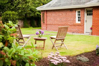 two chairs and a table with flowers on a yard at The Gardener's Cottage in Dunblane