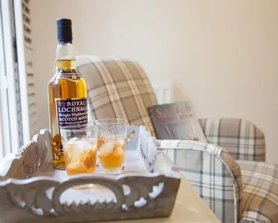 a bottle of alcohol and two glasses on a table at The Gardener's Cottage in Dunblane