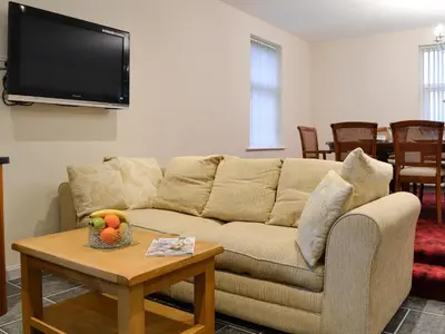a living room with a couch and a table with a bowl of fruit at Liftingstane Farmhouse in Closeburn