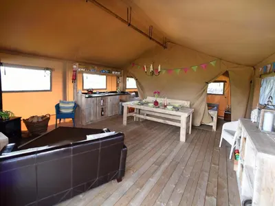 a tent with a table and chairs in a room at Carr's Hill Luxury Safari Tents in Denny
