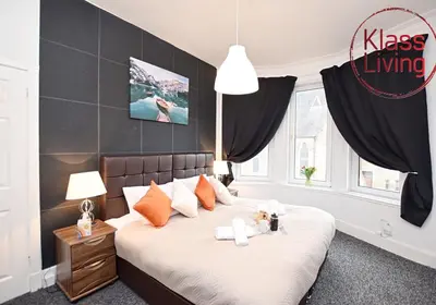 a bedroom with a large bed with orange pillows at Whifflet Apartment by Klass Living Coatbridge in Coatbridge