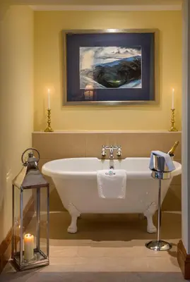 a bath tub in a bathroom with a painting and candles at Glencoe House in Glencoe