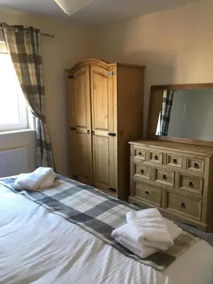 a bedroom with a bed with a dresser and a mirror at 1 Balnakeil, Kirk Road in Oban