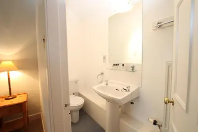 a white bathroom with a toilet and a sink at The Colonsay Hotel in Isle of Colonsay